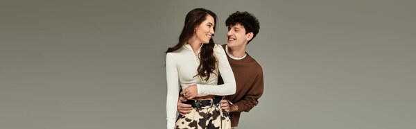 Модная пара делится радостным взаимодействием в современной студии, излучая юношескую энергию.