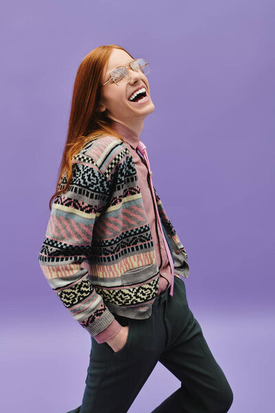 Молодой педик с длинными рыжими волосами радостно гуляет, одетый в модный, красочный наряд.