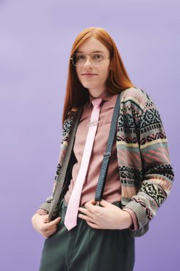 Moda ileri görüşlü, uzun kızıl saçlı genç adam modaya uygun kıyafetlerini modern bir ortamda sergiliyor..