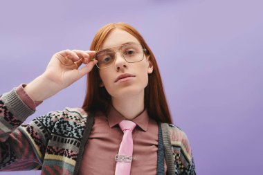 Young queer man with long red hair dons glasses and a tie, showcasing modern fashion flair. clipart