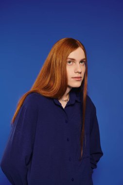 Çarpıcı kızıl saçlı genç bir adam modasını modern bir sahnede sergiliyor..