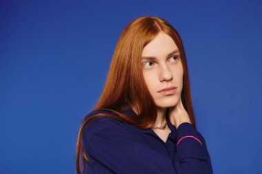 Genç, eşcinsel bir adam, kendine güvenen uzun kızıl saçlarıyla şık görünümünü sergiliyor..