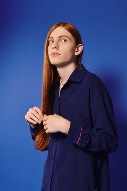 Şık, kızıl saçlı genç bir adam zarif bir şekilde duruyor, eşsiz tarzını sergiliyor..