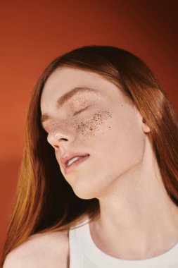 Sıcak bir atmosferde, genç tuhaf bir adam zarif bir şekilde uzun kızıl saçlı ve parlak aksanlı poz verir..