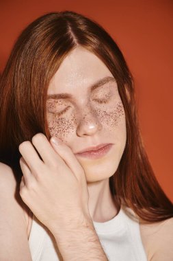 Uzun kızıl saçlı, şık, genç bir nonoş, çillerini göstererek bir anı kucaklıyor..