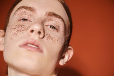 Kızıl saçlı, benzersiz çilleri olan şık bir genç adam kendinden emin, modern bir cazibe yayıyor..