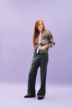 Uzun kızıl saçlı tuhaf genç adam renkli bir arka plana karşı şık kıyafetler sergiliyor..