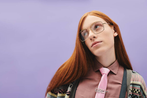 Уверенный в себе молодой человек с рыжими волосами и модными очками творчески выставляет напоказ свой уникальный стиль.