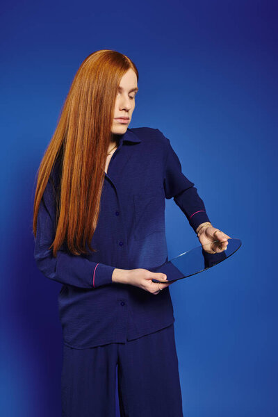 A stylish queer person examines a unique reflective object, embodying creativity.