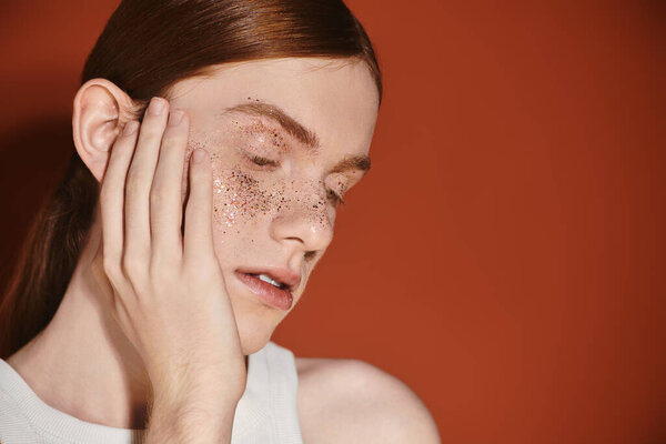 Молодой человек с длинными рыжими волосами демонстрирует свой стильный вид на ярком фоне.