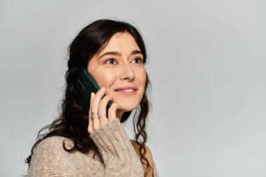 Şık bir stüdyo ortamında telefon konuşmasından hoşlanan genç bir kadın..