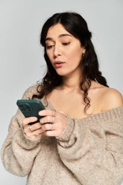 Samimi bir stüdyo ortamında telefonuyla meşgul olan genç bir kadın..