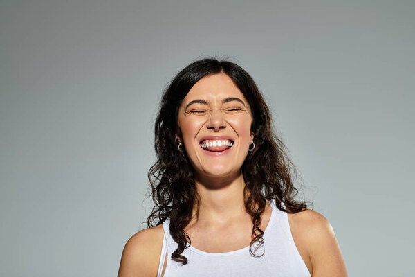 Smiling young woman in casual attire, enjoying a light moment in the studio setting.