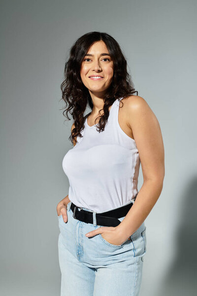 Plus size woman exudes confidence in a stylish white tank top and casual denim.