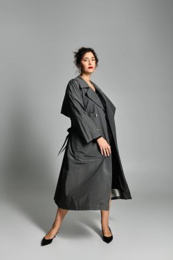 Modern stüdyo ortamında zarif giyinmiş genç bir kadın zarif pozlar veriyor..