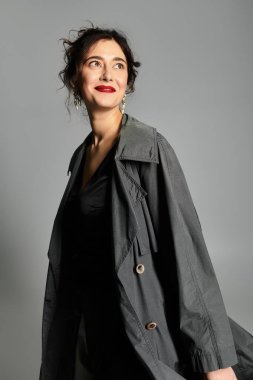 Zarif esmer kadın zarif bir şekilde gri bir arka plana karşı şık bir şekilde poz veriyor..