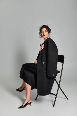 Zarif esmer kadın, gri arka plana karşı şık bir şekilde poz veriyor..