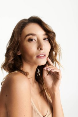 Şık, genç bir kadın şık iç çamaşırlarıyla poz veriyor. Yumuşak ve zarif bir ifadeyle..