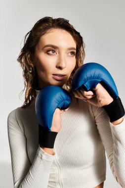 Dinamik genç kadın, modern stüdyo ortamında boks eldivenleriyle kendine güvenini gösteriyor..