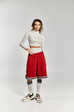 Minimalist bir stüdyo ortamında modern sokak kıyafetleri sergileyen şık bir kadın..