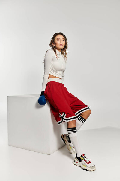 Young beautiful woman showcases trendy sporty fashion in a modern studio setting.