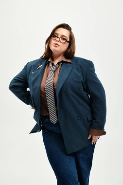 Genç ve cüsseli bir kadın kendine güvenerek şık bir iş elbisesi içinde ve modaya uygun şekilde poz veriyor..