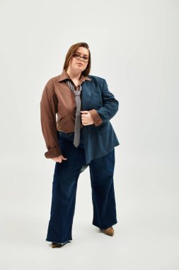 Genç ve cüsseli bir kadın, kendine güvenen iki tonlu şık bir elbise içinde poz verir ve tarzını sergiler..