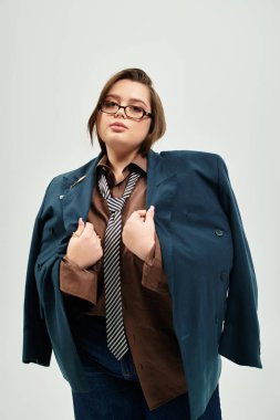 Ayrıca cüsseli bir kadın, kendine güveni ve tarzıyla gösteriş yapan, büyük bir spor ceket ve kravat takıyor..