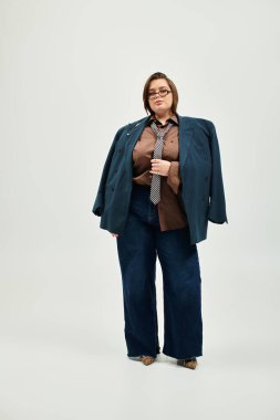 Kendine güveni yüksek genç bir kadın şık bir spor ceket ve kravatla tarz sergiliyor..