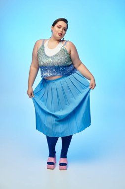 Genç bir kadın parıldayan bir bluz ve canlı bir etekle güzellik saçıyor, eşsiz tarzını sergiliyor..