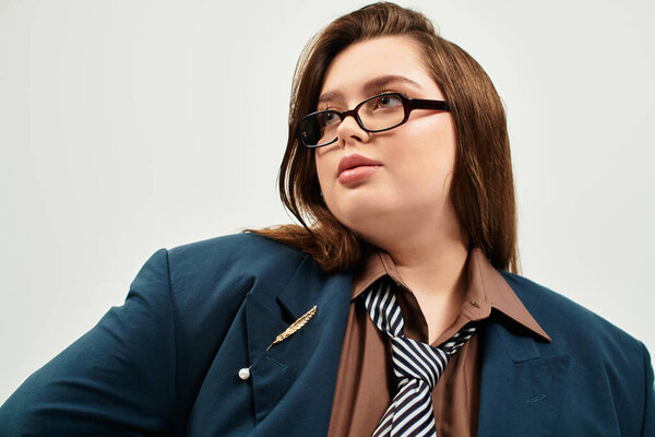 Confident plus size woman shines in an oversized blazer and trendy tie, embracing her beauty.