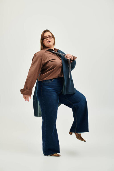 Brightly lit backdrop highlights a young plus size woman expressing her unique fashion sense.