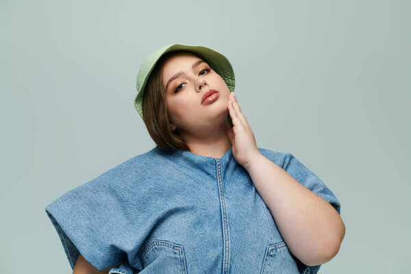 A young plus size woman showcases her beauty while confidently posing in a stylish denim outfit.