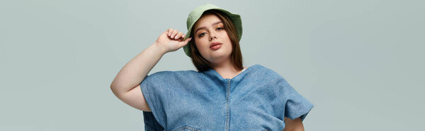 A young plus size woman poses confidently in a trendy denim ensemble, showcasing her unique style.