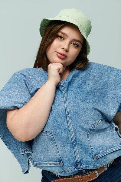 Confident plus size woman models stylish denim and a trendy hat with a delightful smile.