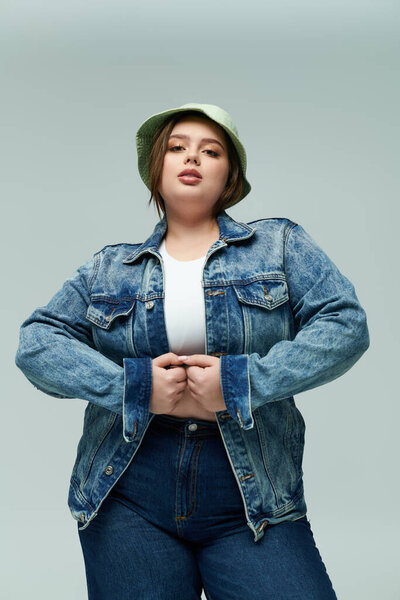 Young woman showcases a stylish denim jacket and bucket hat, radiating confidence and beauty.