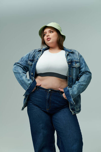 Уверенная в себе плюс размер женщина демонстрирует свой стиль с модной джинсовой курткой и джинсами.