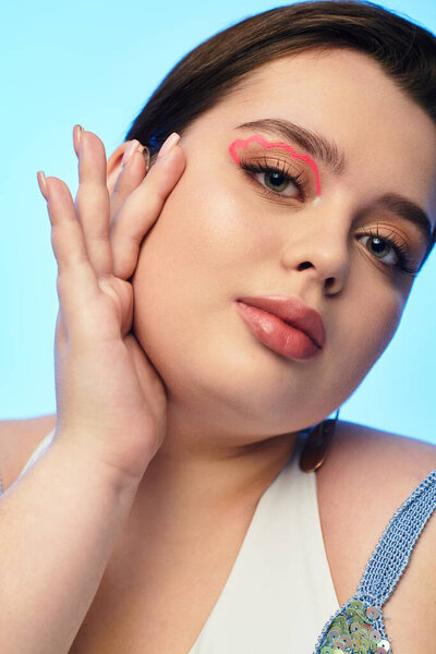 Молодая женщина плюс размер подчеркивает ее потрясающий макияж, мягко трогая ее лицо.