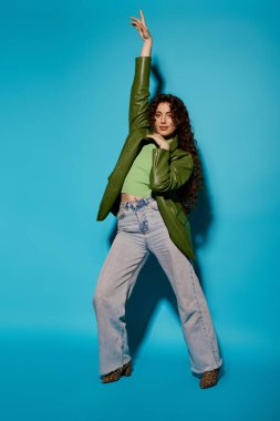 Genç bir kadın cesur yeşil elbisesi ve neşeli pozuyla moda anlayışını sergiliyor..