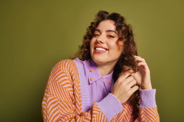 Genç kadın, içeride poz verirken neşe saçarak saçlarını düzenliyor..