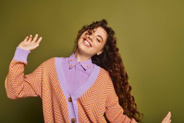 A cheerful young woman with beautiful curly hair showcases her stylish outfit while dancing. clipart