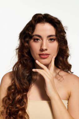 Kendine güvenen genç bir kadın, güzelliğini ve stilini yumuşak bukleleri ve zarif duruşuyla sergiliyor.