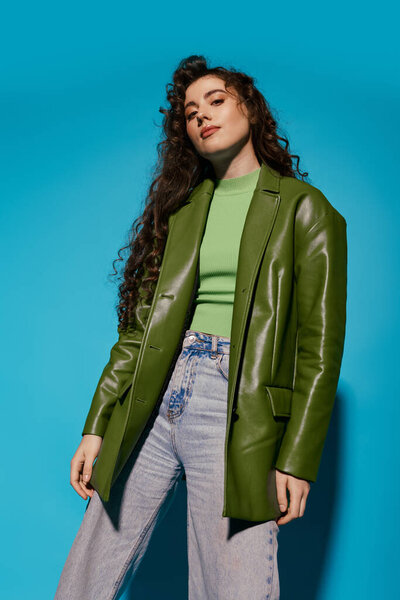 A beautiful young woman showcases her fashionable outfit with a bold green blazer and relaxed jeans.