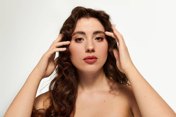 Stylish woman presents a serene expression while gently touching her hair, exuding confidence.