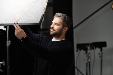 Yetenekli bir işçi modern bir stüdyodaki ışıklandırma düzeneğini kusursuz aydınlatma için geliştirir..