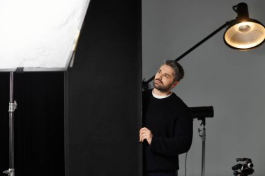 Stüdyo malzemelerini ustalıkla kullanan bir adam profesyonel bir çekim için hazırlanıyor..