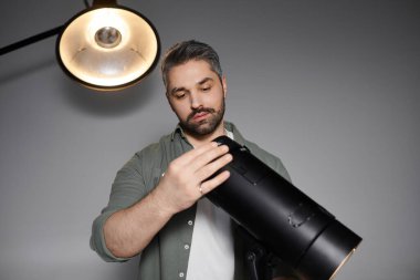 Stüdyoda çarpıcı portreler çekmeden önce odaklanmış bir profesyonel kamera ışığı donanımını kontrol ediyor..