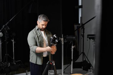 Odaklanmış bir adam fotoğraf stüdyosunda kamera ekipmanlarını hazırlıyor..