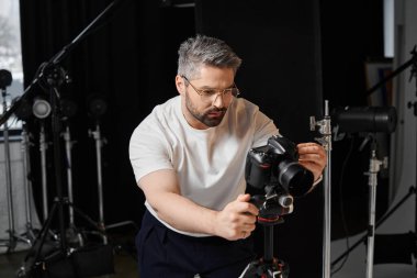 Bir adam profesyonel fotoğraf stüdyosunda kamera ekipmanını ayarlamakta iyidir..