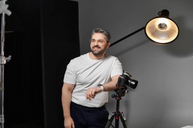 Yetenekli bir birey kameranın yanında duruyor. Çekici bir fotoğraf çekimi için hazır..